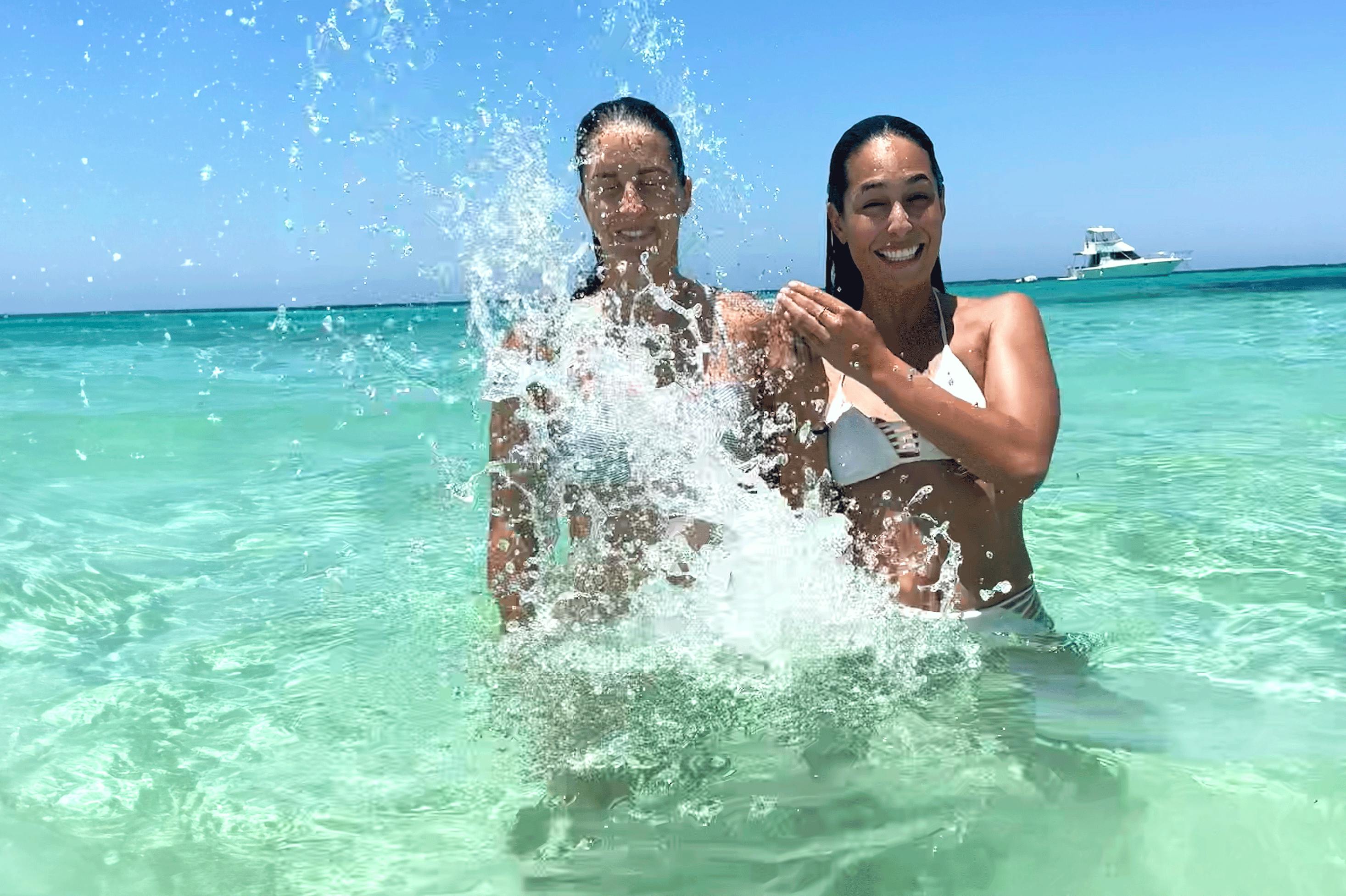 Two woman play in the blue waters of the south pacific